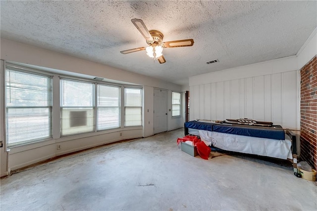 bedroom featuring concrete floors, ceiling fan, brick wall, and a textured ceiling