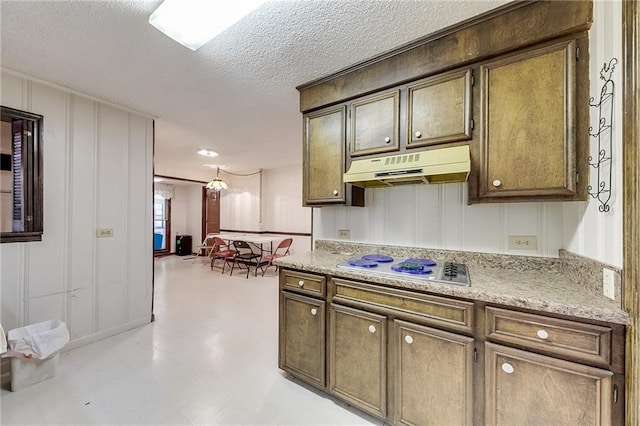 kitchen featuring white cooktop, dark brown cabinets, and a textured ceiling