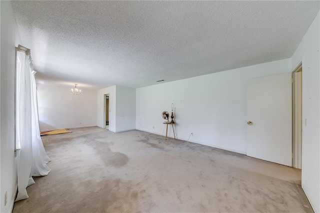 spare room with light colored carpet, an inviting chandelier, and a textured ceiling