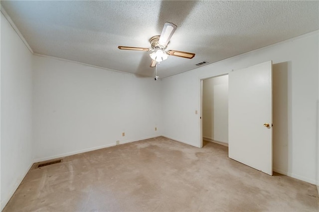 empty room featuring ceiling fan, a textured ceiling, and light carpet