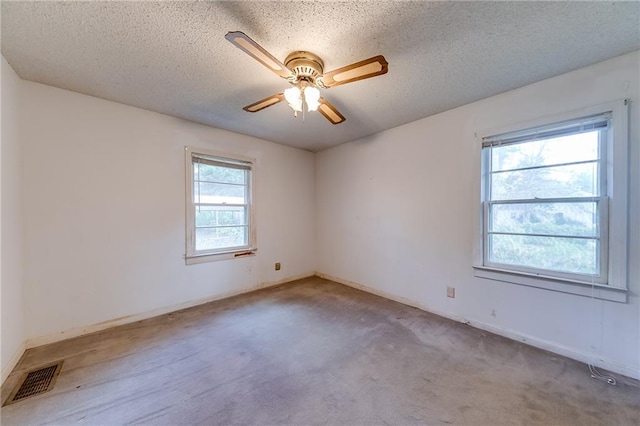 spare room with light carpet, a healthy amount of sunlight, ceiling fan, and a textured ceiling