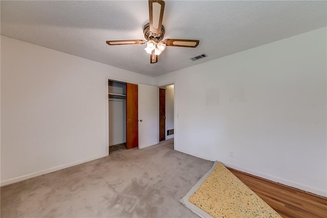 unfurnished bedroom with ceiling fan, light colored carpet, a textured ceiling, and a closet