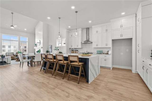 kitchen with tasteful backsplash, double oven, a kitchen island with sink, pendant lighting, and white cabinetry