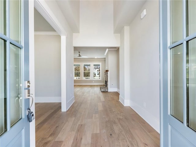 foyer featuring a brick fireplace, light hardwood / wood-style flooring, ceiling fan, and ornamental molding