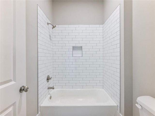 bathroom with tiled shower / bath combo and toilet