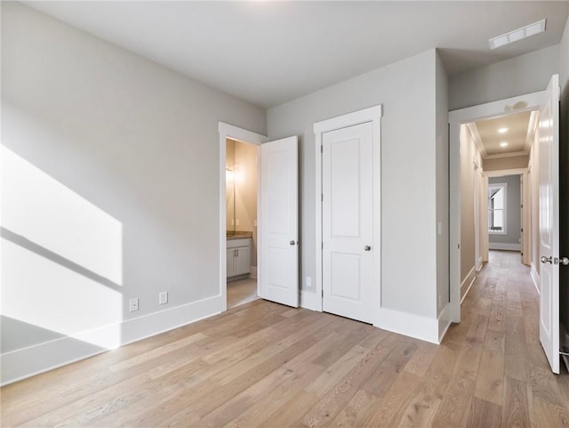 unfurnished bedroom with ensuite bath and light hardwood / wood-style flooring