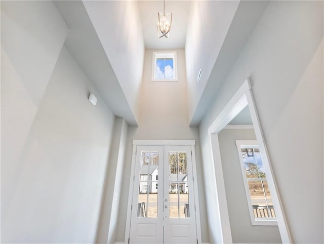 doorway to outside with french doors, a chandelier, and a high ceiling