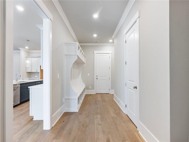 mudroom featuring light hardwood / wood-style flooring, ornamental molding, and sink