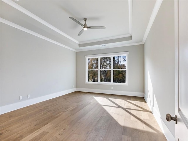 empty room with a raised ceiling, ceiling fan, light hardwood / wood-style flooring, and ornamental molding