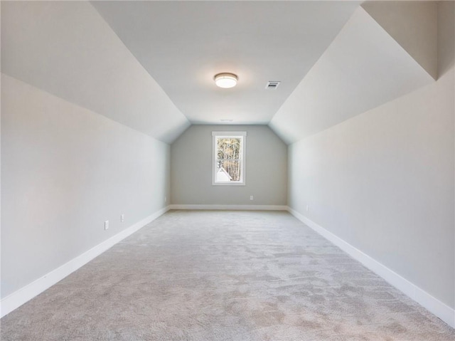 additional living space featuring light carpet and vaulted ceiling