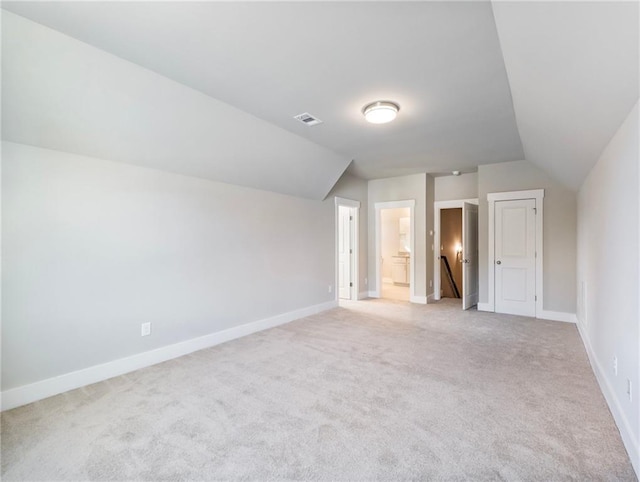 bonus room with light colored carpet and vaulted ceiling