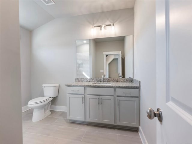 bathroom featuring tile patterned flooring, vanity, toilet, and vaulted ceiling