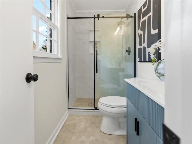 bathroom with toilet, a shower stall, baseboards, and vanity