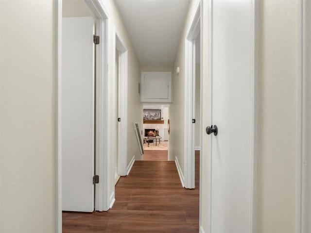 corridor with dark wood-type flooring and baseboards