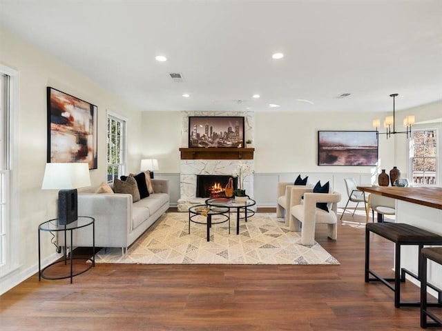 living room with a fireplace, a chandelier, wood finished floors, and recessed lighting