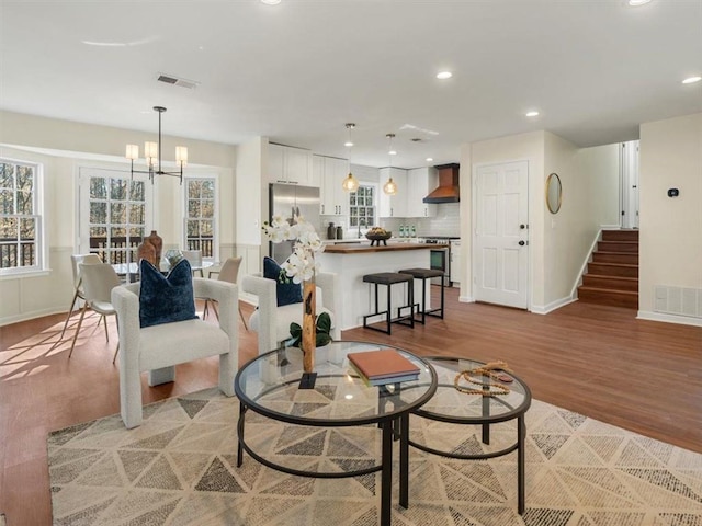 living room with light wood finished floors, baseboards, recessed lighting, a chandelier, and stairs