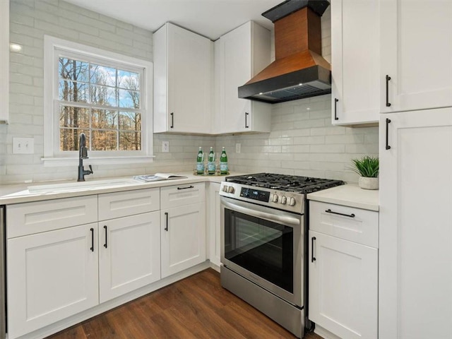 kitchen with stainless steel range with gas stovetop, custom exhaust hood, a sink, light countertops, and backsplash