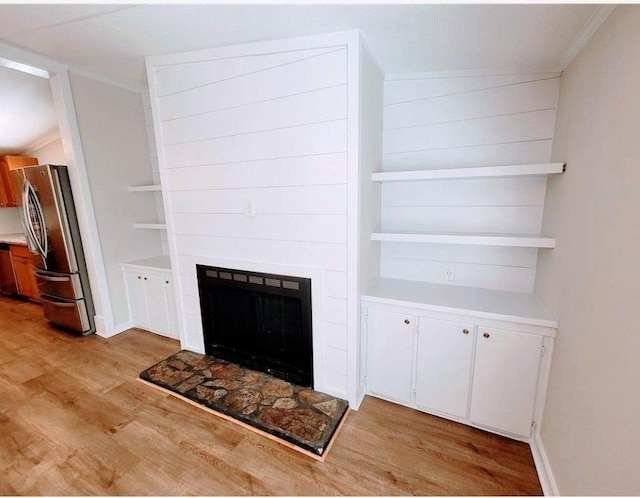 3735 Fir Dr, Buford, GA 30518 - unfurnished living room featuring a fireplace with raised hearth, light wood-style floors, and ornamental molding