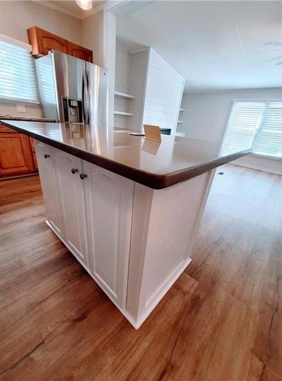 3735 Fir Dr, Buford, GA 30518 - kitchen with light wood-type flooring, a kitchen island, stainless steel refrigerator with ice dispenser, dark countertops, and brown cabinets
