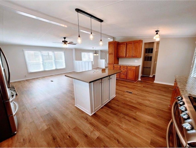 3735 Fir Dr, Buford, GA 30518 - kitchen with pendant lighting, ceiling fan, light wood-type flooring, gas range, and brown cabinets