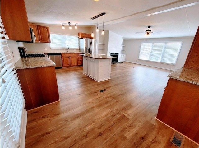 3735 Fir Dr, Buford, GA 30518 - kitchen with light wood-type flooring, vaulted ceiling, visible vents, brown cabinetry, and appliances with stainless steel finishes