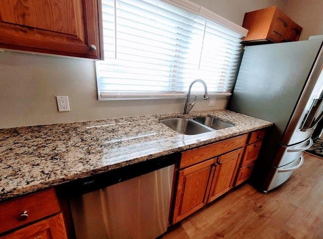 3735 Fir Dr, Buford, GA 30518 - kitchen featuring light wood-type flooring, light stone countertops, brown cabinets, stainless steel appliances, and a sink
