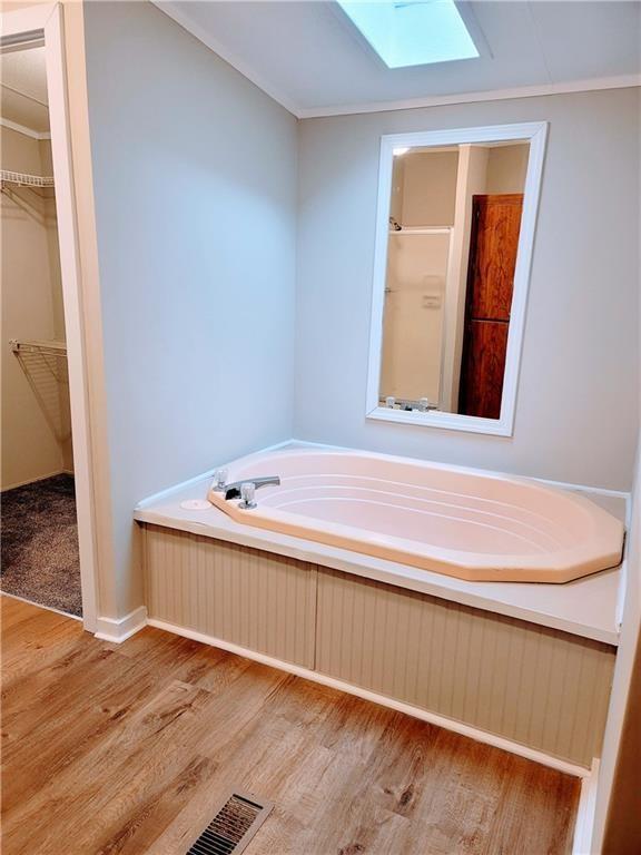 3735 Fir Dr, Buford, GA 30518 - bathroom with a spacious closet, visible vents, a skylight, a garden tub, and wood finished floors