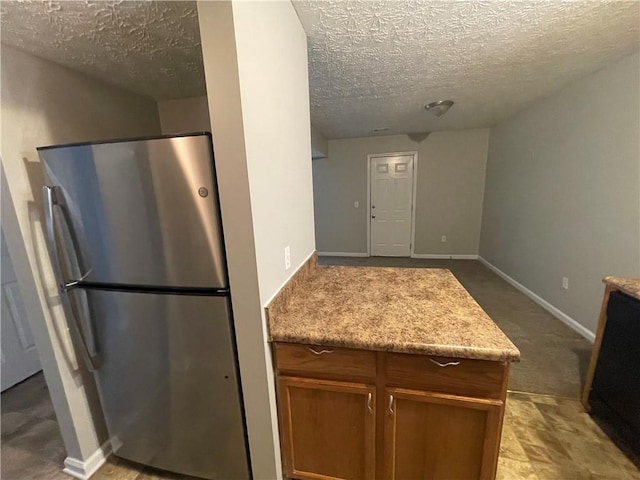 1374 To Lani Farm Rd, Stone Mountain, GA 30083 - kitchen with light countertops, freestanding refrigerator, a textured ceiling, brown cabinetry, and baseboards