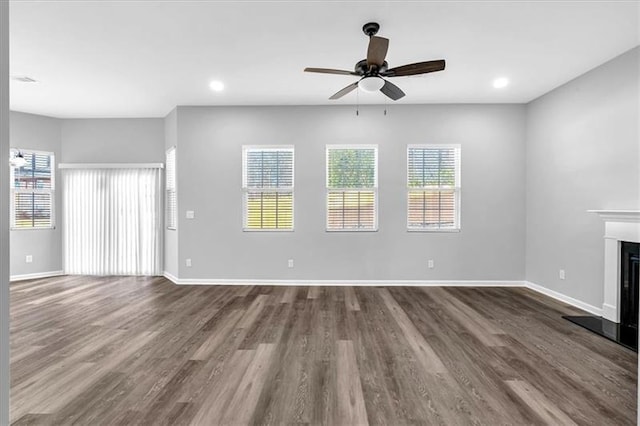 unfurnished living room with baseboards, dark wood finished floors, a ceiling fan, a glass covered fireplace, and recessed lighting