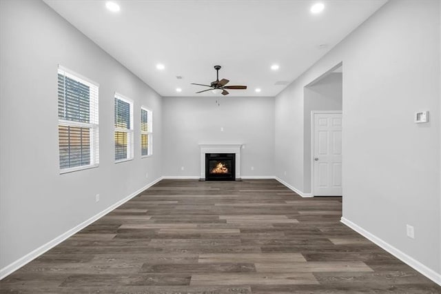 unfurnished living room with baseboards, a fireplace with flush hearth, ceiling fan, dark wood-style flooring, and recessed lighting