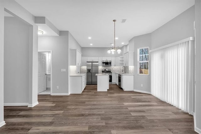 kitchen with white cabinets, decorative backsplash, dark wood-type flooring, stainless steel appliances, and a sink