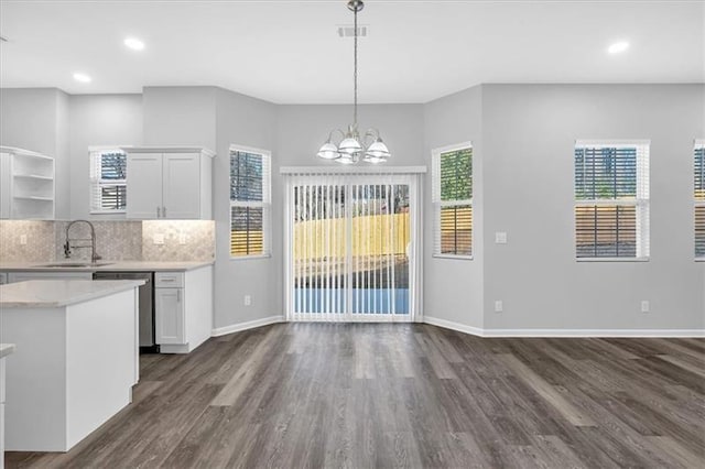 kitchen featuring dark wood-style floors, light countertops, stainless steel dishwasher, open shelves, and a sink