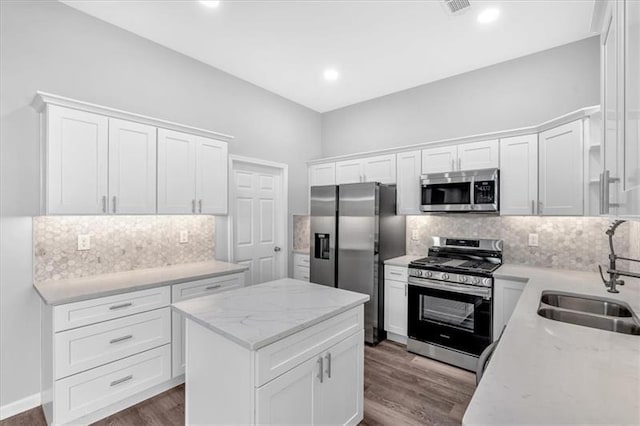 kitchen featuring appliances with stainless steel finishes, dark wood-style flooring, a sink, and white cabinets