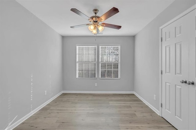 spare room with a ceiling fan, light wood-type flooring, and baseboards