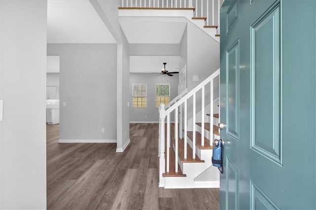 foyer entrance with baseboards, ceiling fan, stairway, and dark wood-style flooring