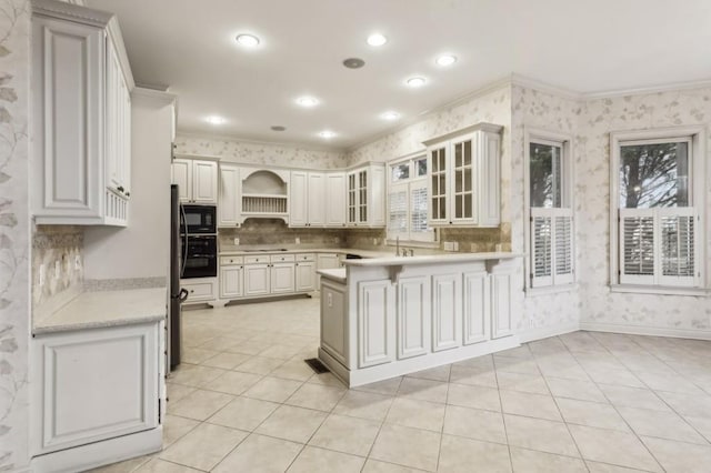 kitchen featuring white cabinets, ornamental molding, kitchen peninsula, and black appliances