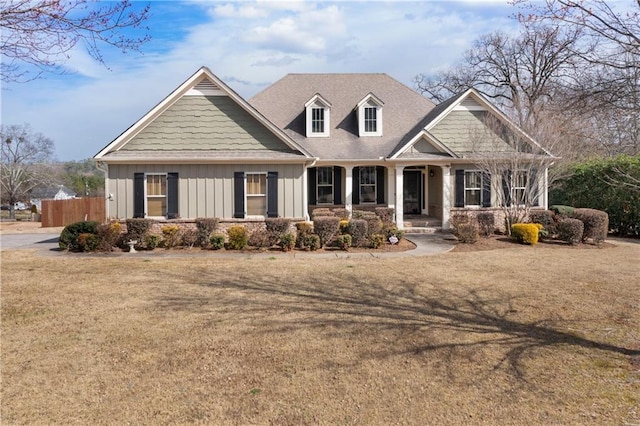 craftsman-style house with board and batten siding, covered porch, fence, and a front lawn