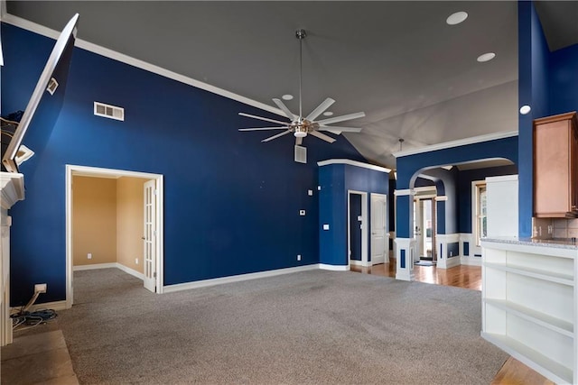 unfurnished living room with visible vents, arched walkways, a ceiling fan, carpet flooring, and high vaulted ceiling