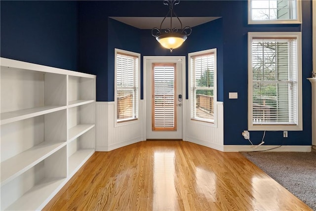 doorway to outside featuring wainscoting and wood finished floors