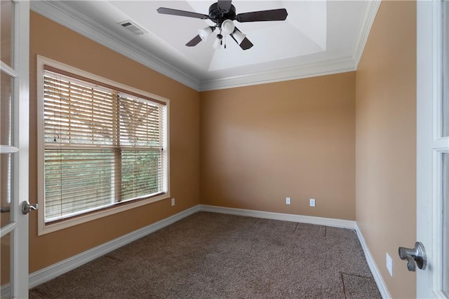 carpeted spare room featuring a raised ceiling, visible vents, ornamental molding, ceiling fan, and baseboards