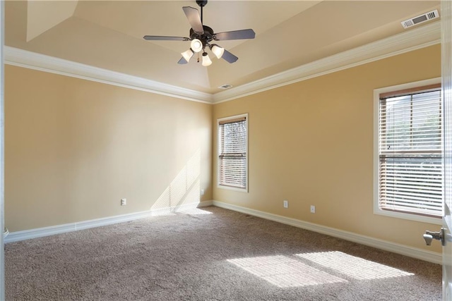 carpeted spare room with ornamental molding, visible vents, baseboards, and a ceiling fan