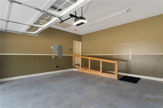 garage featuring a wainscoted wall, electric panel, and a garage door opener