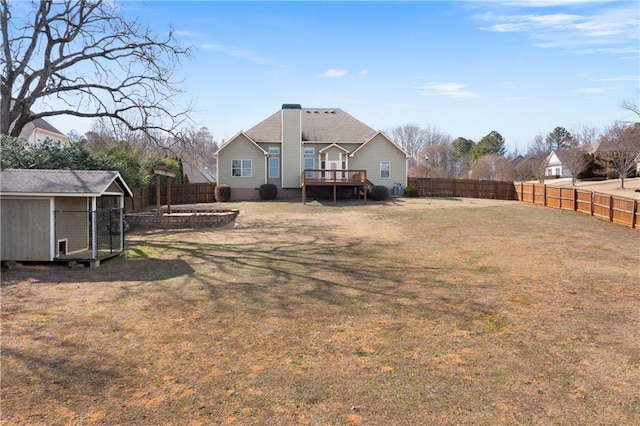 back of house with a fenced backyard, a deck, a lawn, and an outdoor structure