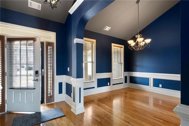 foyer with wainscoting, wood finished floors, visible vents, and an inviting chandelier