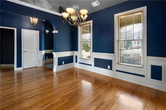 unfurnished dining area featuring visible vents, a notable chandelier, and wood finished floors