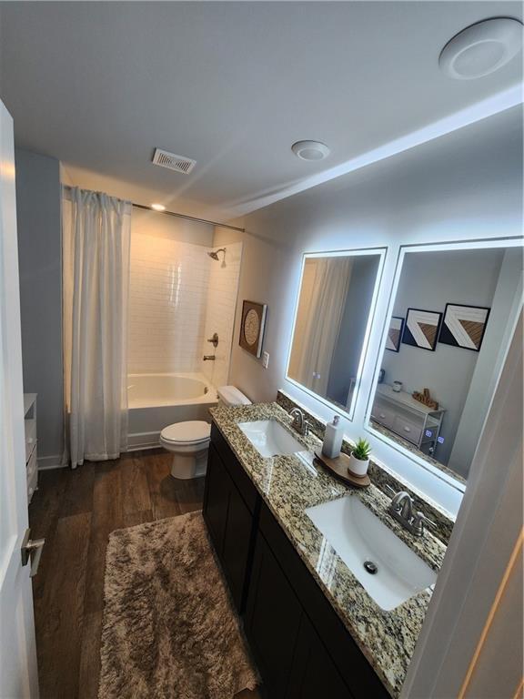 full bath featuring wood finished floors, a sink, shower / tub combo, and visible vents