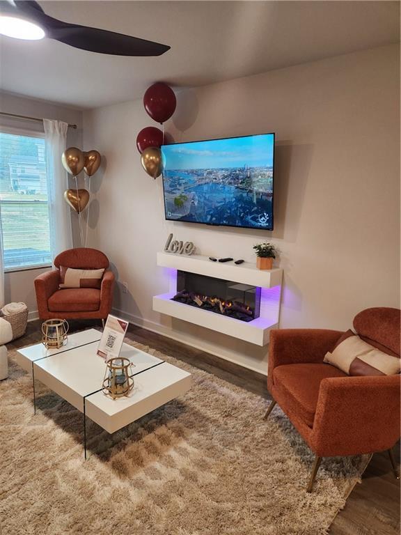 living room with baseboards, wood finished floors, and a glass covered fireplace