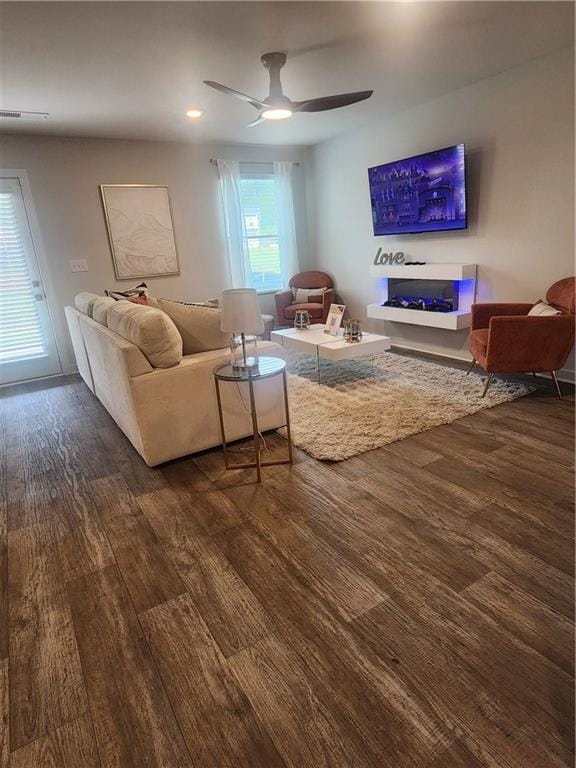 living room featuring visible vents, wood finished floors, and a ceiling fan