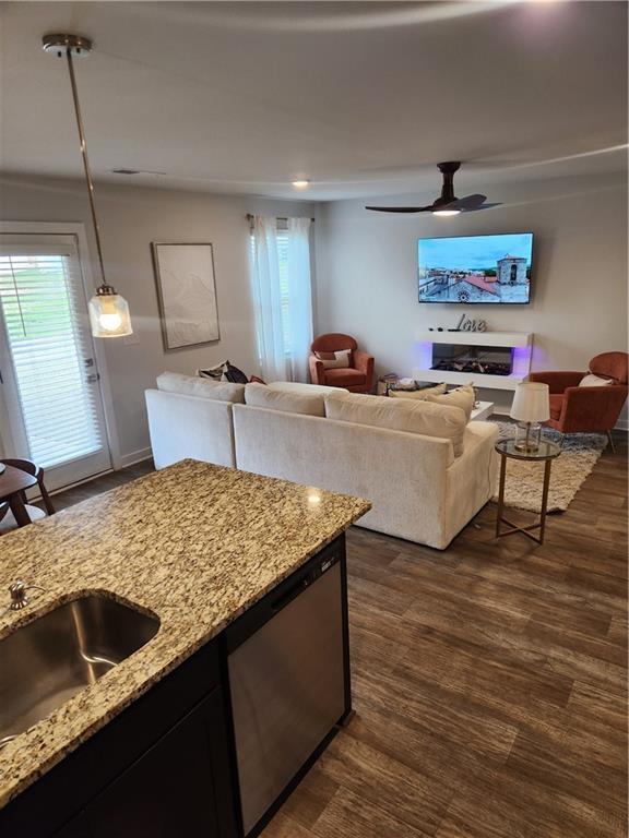 kitchen with dark wood-style flooring, light stone counters, open floor plan, and dishwasher