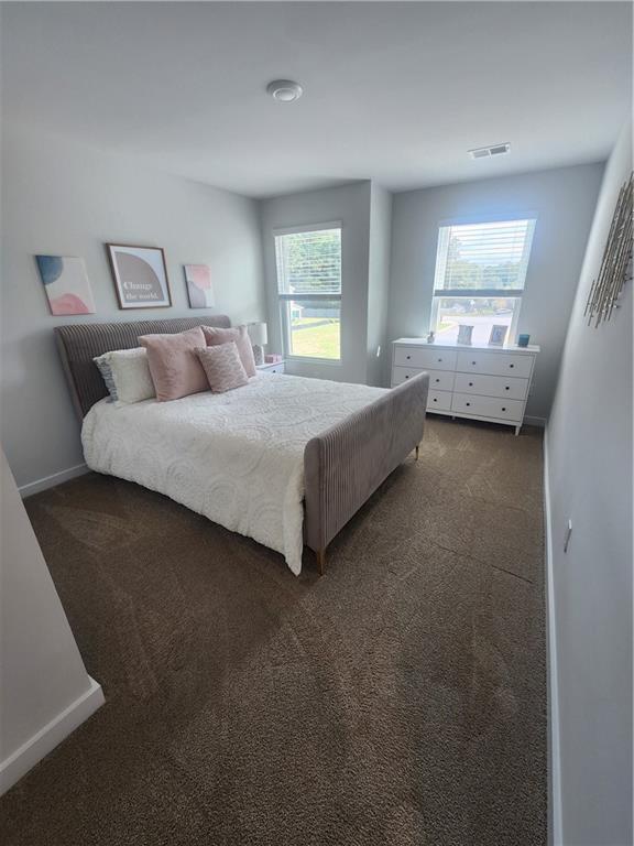 bedroom with baseboards, visible vents, and dark carpet